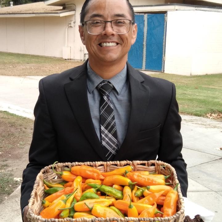 A community leader holding a basket of harvested peppers